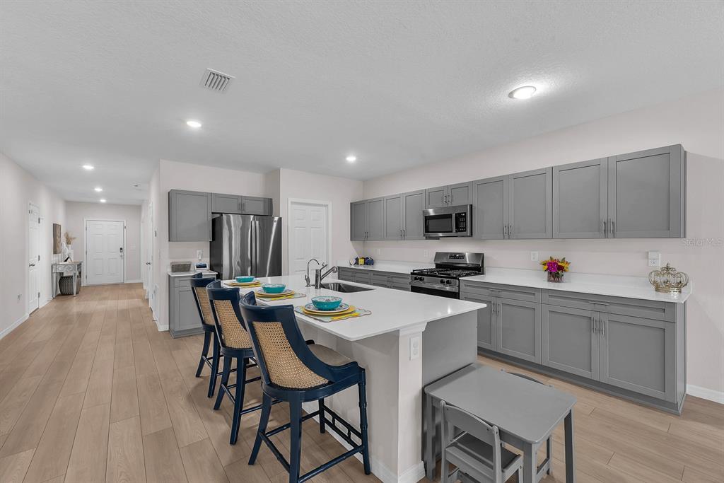 12952 Wellspring Drive Lithia, FL 33547 - Photo 7 of 46 a kitchen with a dining table chairs refrigerator and cabinets