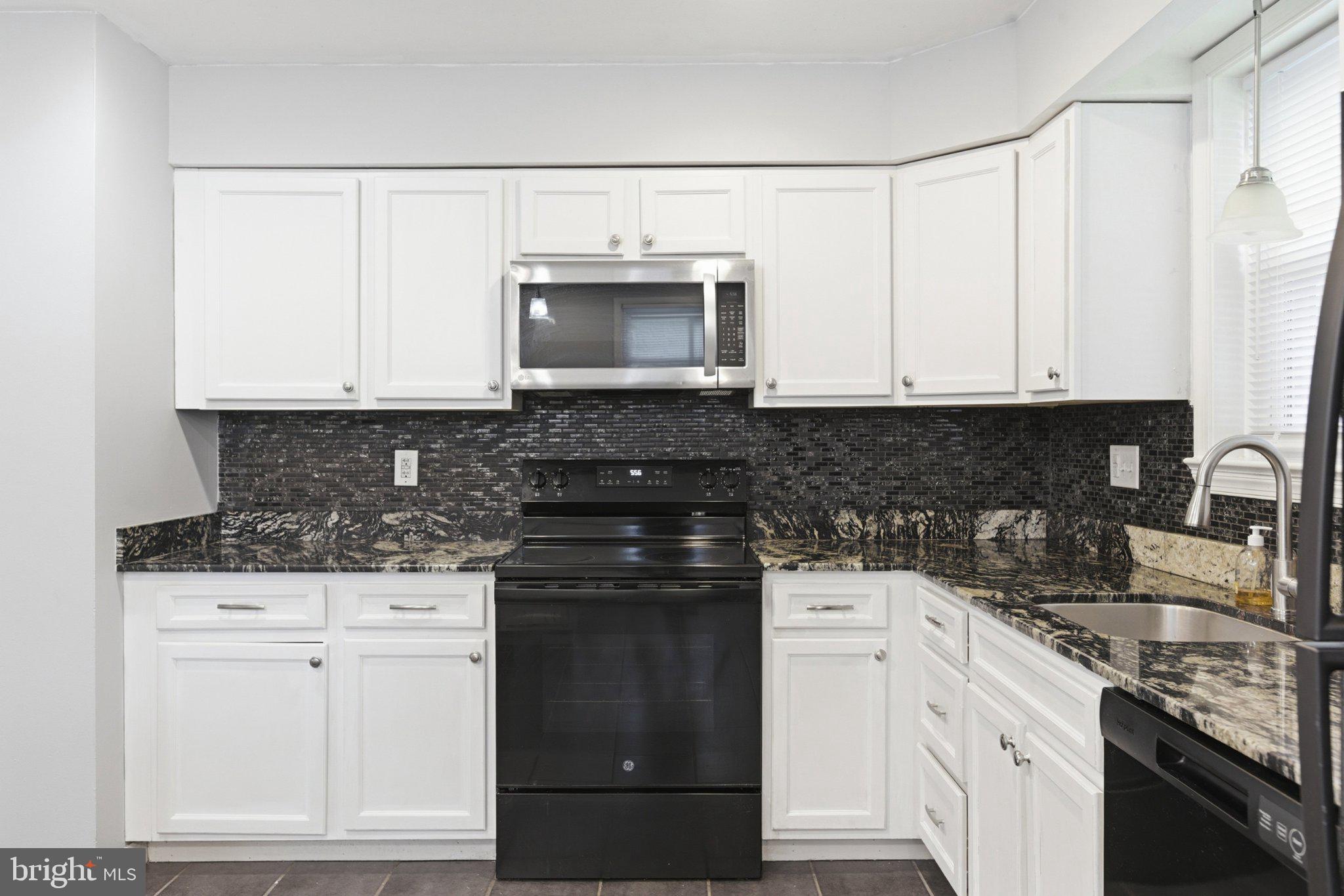12908 Glynis Road Clinton, MD 20735 - Photo 7 of 32 a kitchen with granite countertop white cabinets and black appliances