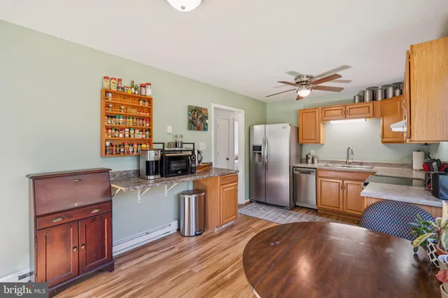 a kitchen with granite countertop a stove top oven a sink dishwasher a dining table and chairs with wooden floor