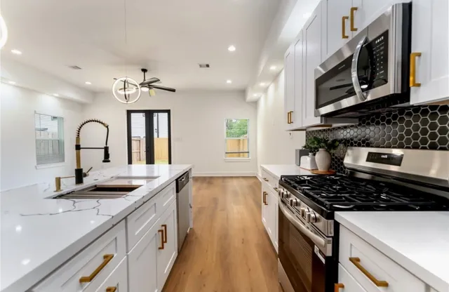 a kitchen with stainless steel appliances a sink stove and cabinets