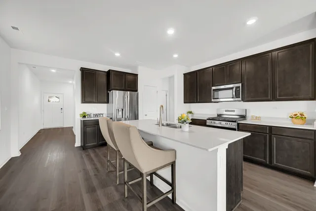 a kitchen with stainless steel appliances a stove top oven a sink dishwasher a refrigerator and cabinets with wooden floor