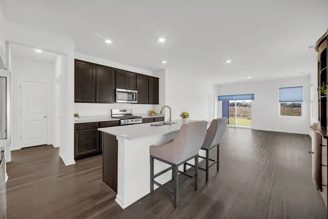 a kitchen with stainless steel appliances a microwave a stove a sink a refrigerator dining table and chairs