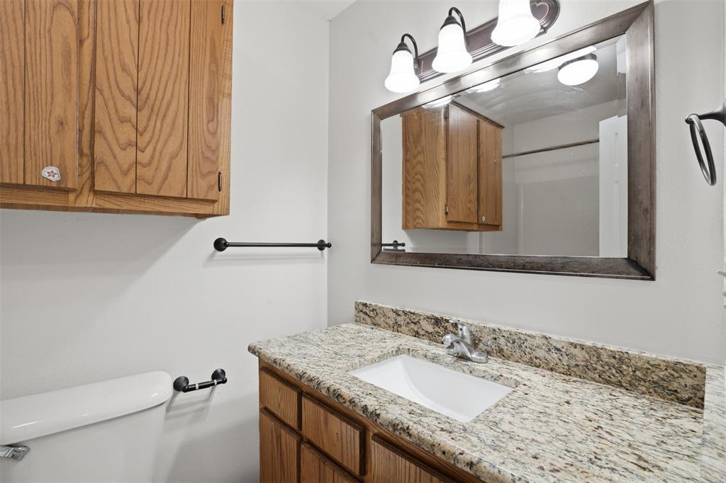 106 Shaw Street, Unit 106 Tom Bean, TX 75491 - Photo 18 of 25 a bathroom with a granite countertop sink a mirror and a toilet