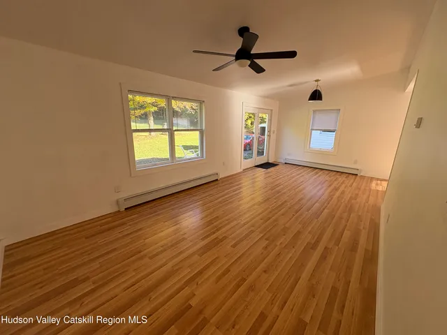 a view of empty room with wooden floor and fan