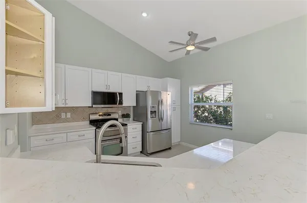 a kitchen that has a refrigerator a stove and white cabinets