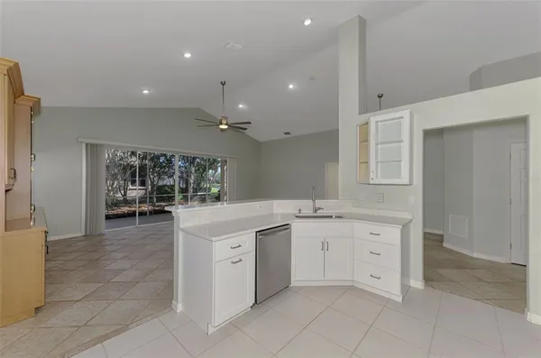 a view of a kitchen with a sink and dishwasher a refrigerator with white cabinets