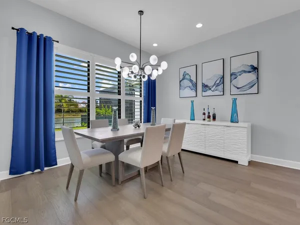 a dining room with wooden floor a chandelier a wooden table and chairs