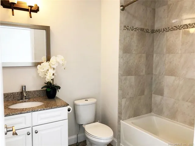 a bathroom with a granite countertop sink a toilet and shower