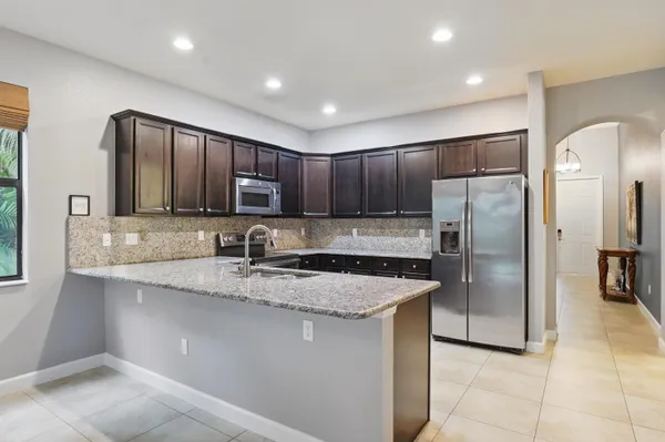 a kitchen with stainless steel appliances granite countertop a refrigerator a sink a stove a microwave and wooden cabinets
