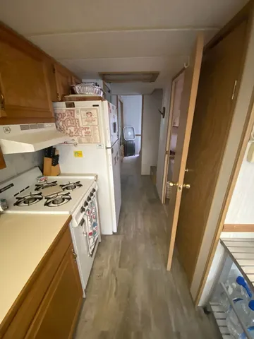 a kitchen with a stove a refrigerator and a wooden floor