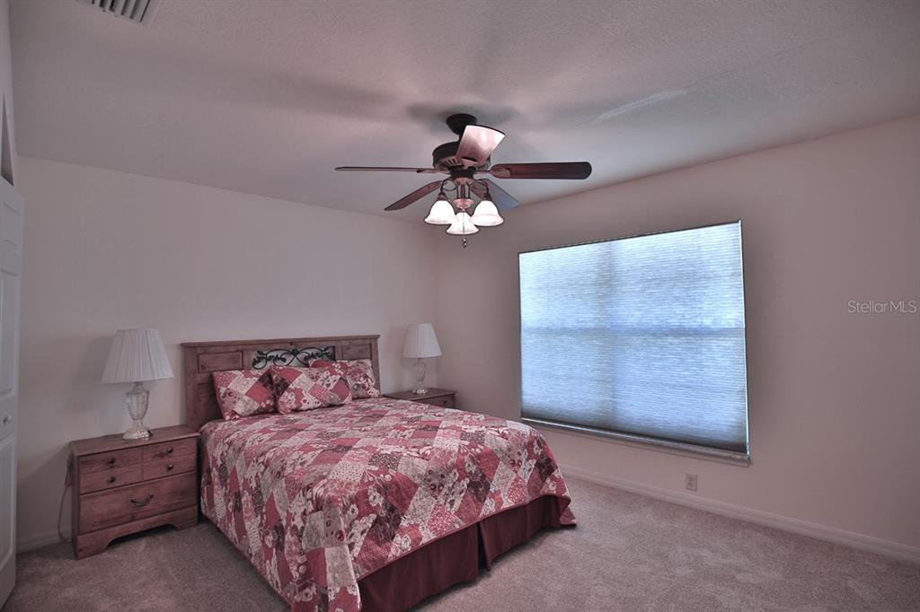 12219 Southwest 26th Street Ocala, FL 34481 - Photo 23 of 63 a bedroom with a large bed chandelier and a window