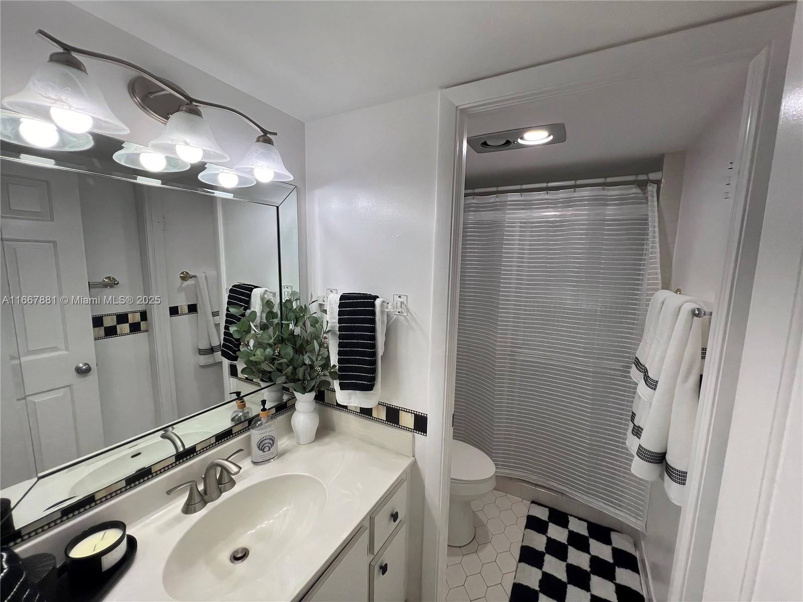 1280 Surf Road, Unit 103 Singer Island, FL 33404 - Photo 23 of 55 a bathroom with a sink a toilet a shower and a mirror