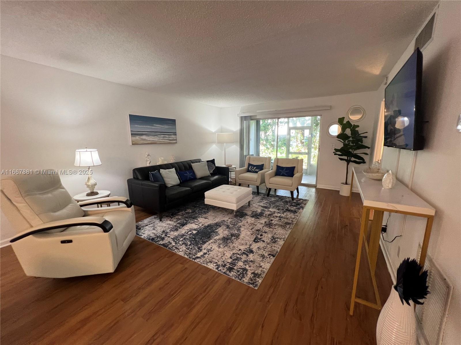 1280 Surf Road, Unit 103 Singer Island, FL 33404 - Photo 4 of 55 a living room with furniture a flat screen tv and a wooden floor