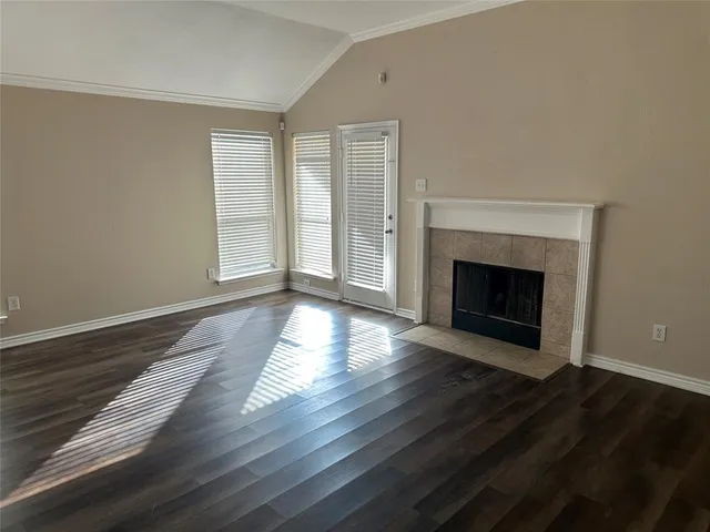 a view of an empty room with wooden floor fireplace and a window