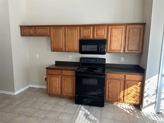 a kitchen with granite countertop a stove top oven microwave and cabinets