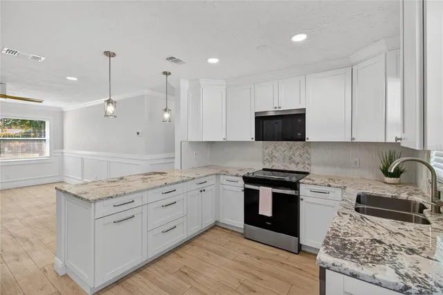 a kitchen with stainless steel appliances granite countertop a stove a sink and a microwave