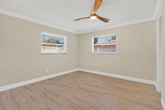 a view of empty room with wooden floor and fan