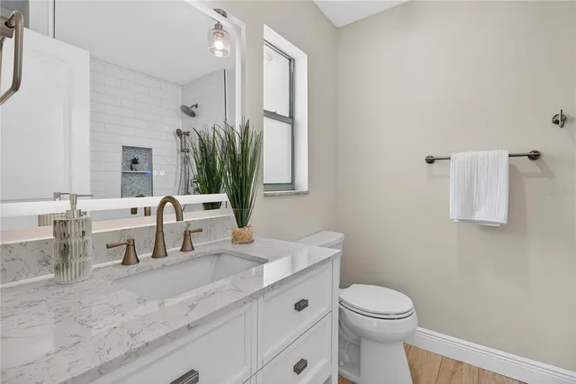 a bathroom with a granite countertop sink mirror vanity and toilet