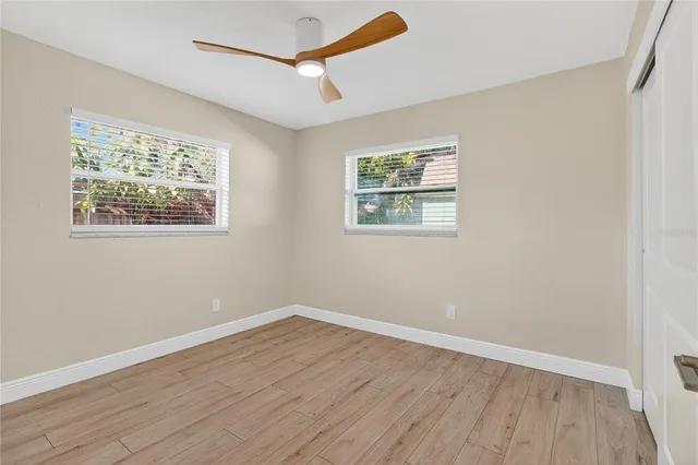 a view of an empty room with wooden floor and a window