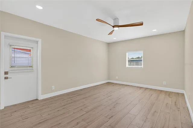a view of an empty room with wooden floor and a window