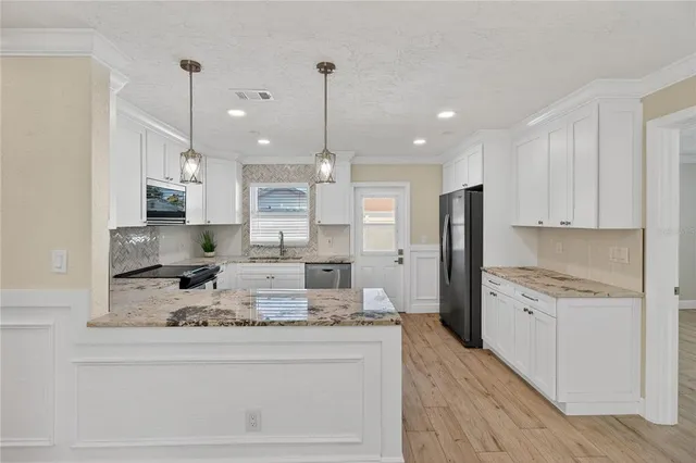 a large kitchen with kitchen island a stove a sink a refrigerator and chandelier