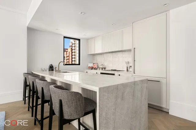 a kitchen with stainless steel appliances a sink a stove a refrigerator with white cabinets and wooden floor