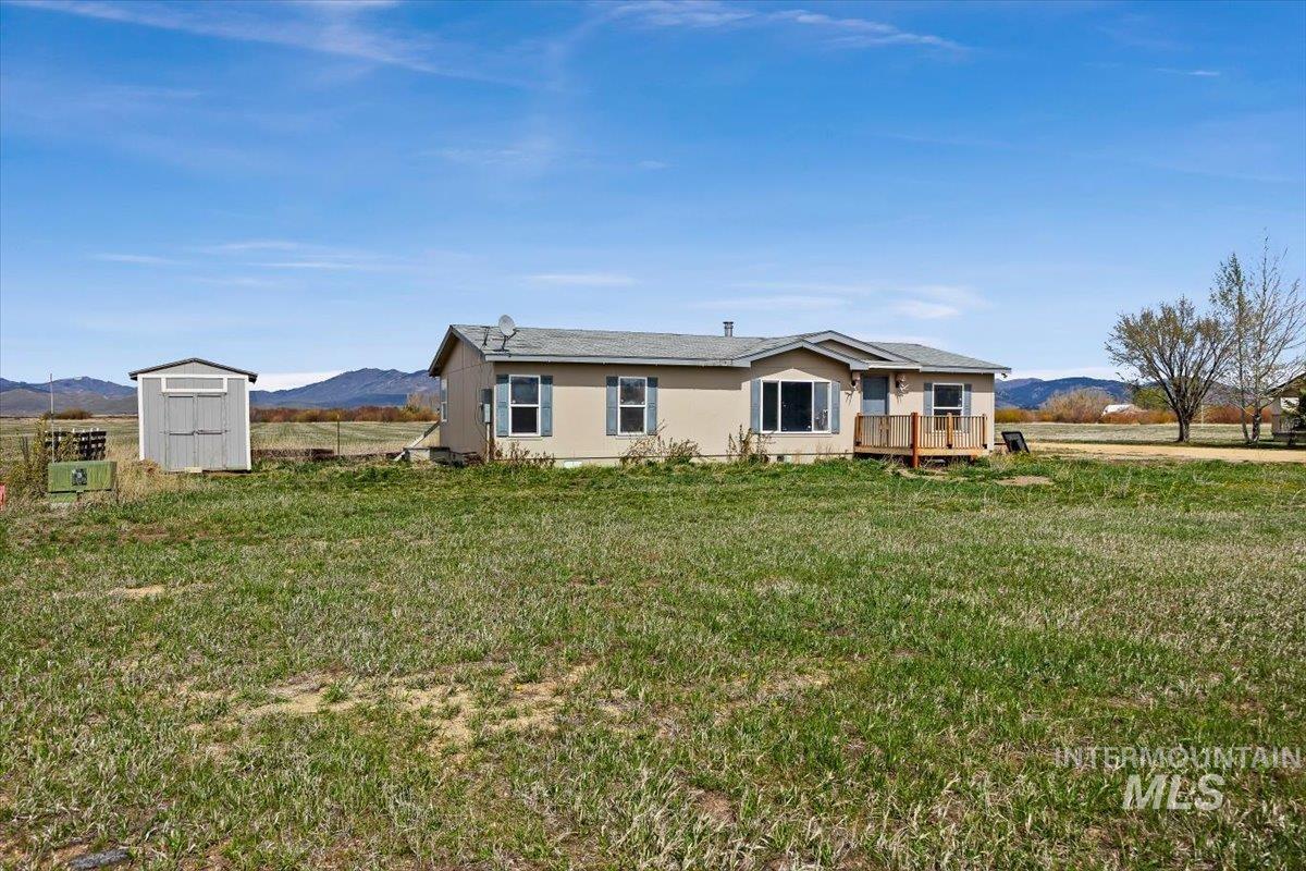 Rear view of property featuring a mountain view, a storage shed, and a lawn
