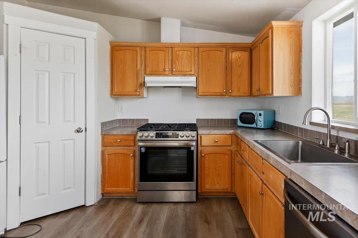 501 Timber Avenue Fairfield, ID 83327 - Photo 12 of 27 Kitchen with stainless steel appliances, dark wood-style floors, lofted ceiling, wood finish cabinets, and light countertops