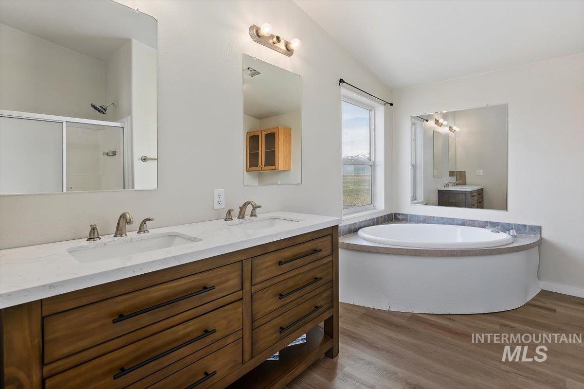 501 Timber Avenue Fairfield, ID 83327 - Photo 15 of 27 Full bath with double vanity, a bath, dark wood-style flooring, and a shower stall
