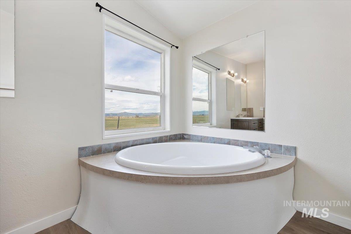501 Timber Avenue Fairfield, ID 83327 - Photo 16 of 27 Bathroom featuring a garden tub, dark wood-type flooring, vanity, and a textured wall