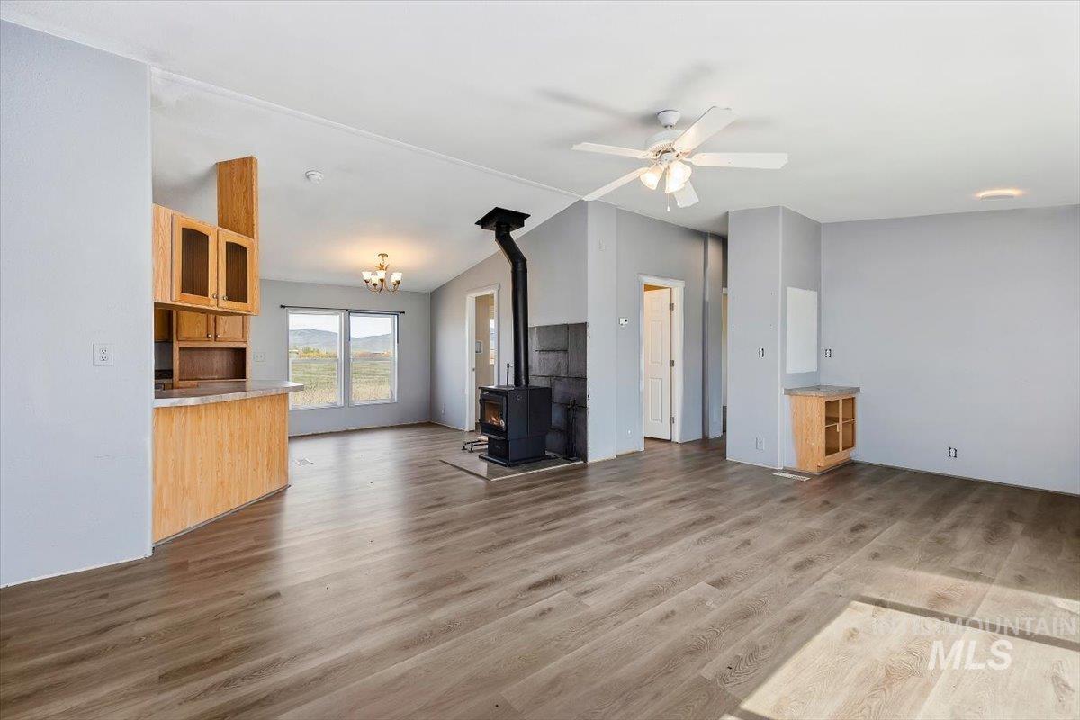 501 Timber Avenue Fairfield, ID 83327 - Photo 5 of 27 Unfurnished living room featuring a wood stove, ceiling fan, lofted ceiling, light wood-type flooring, and suspended lighting