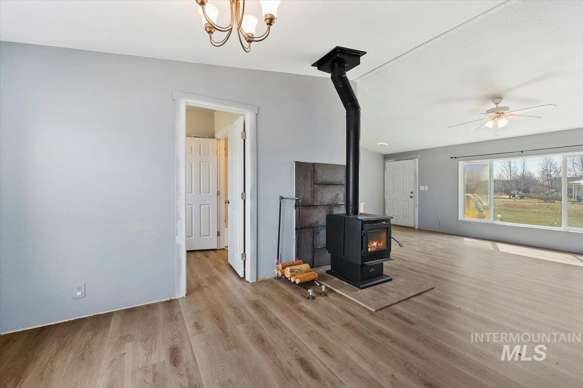 501 Timber Avenue Fairfield, ID 83327 - Photo 7 of 27 Unfurnished living room featuring a wood stove, light wood finished floors, a ceiling fan, and hanging lights