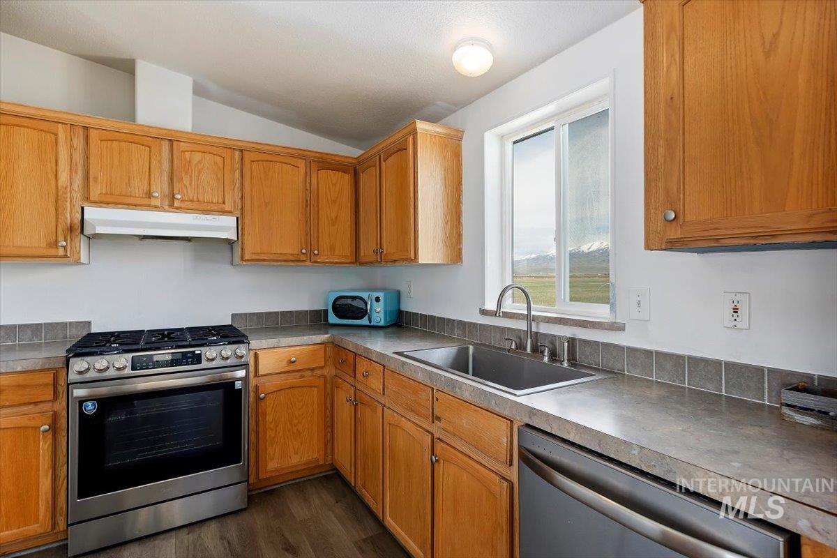 501 Timber Avenue Fairfield, ID 83327 - Photo 9 of 27 Kitchen with stainless steel appliances, wood finish cabinets, dark wood-type flooring, vaulted ceiling, and light countertops