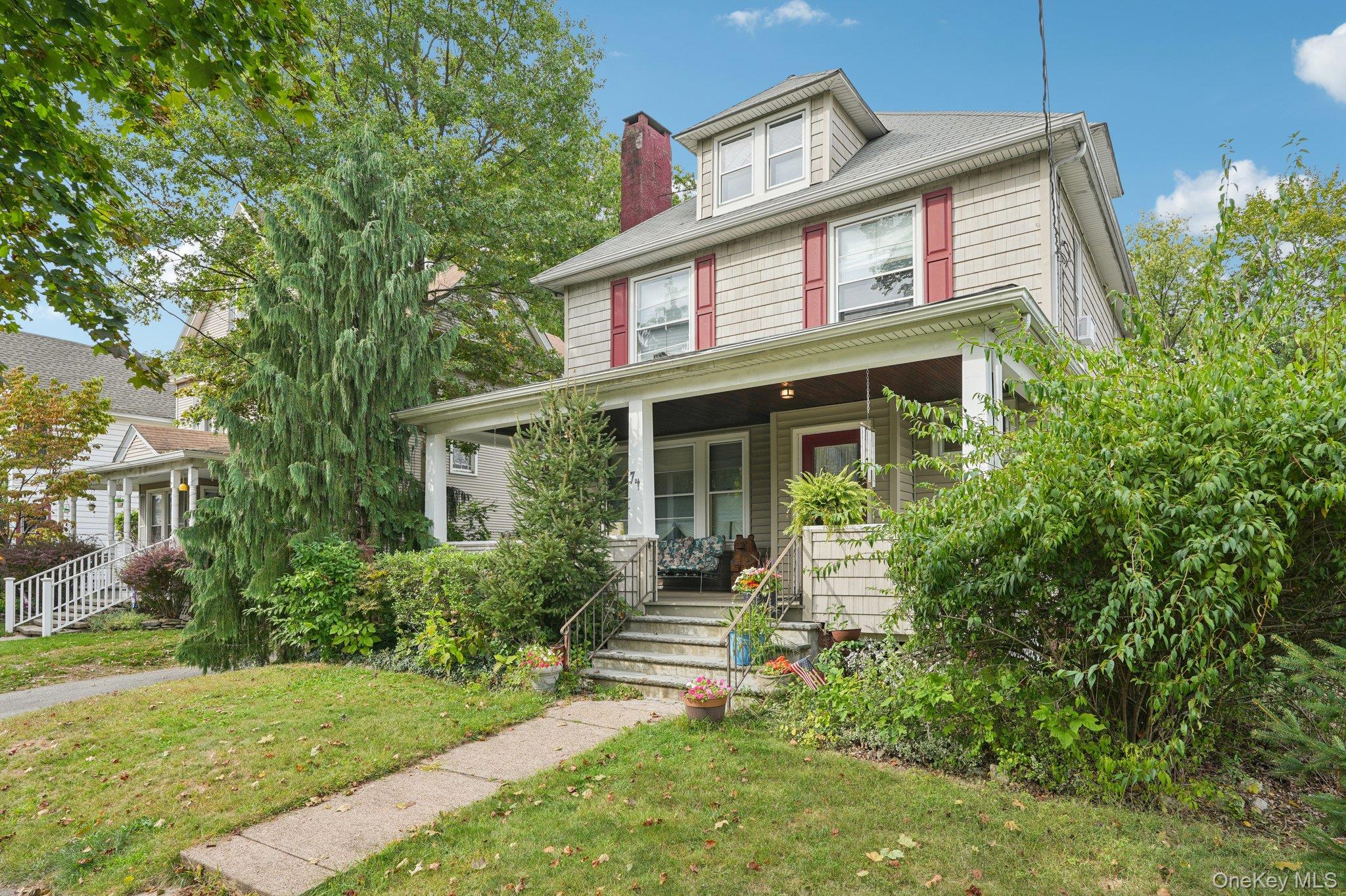 American foursquare style home with a porch, a front lawn, and a chimney