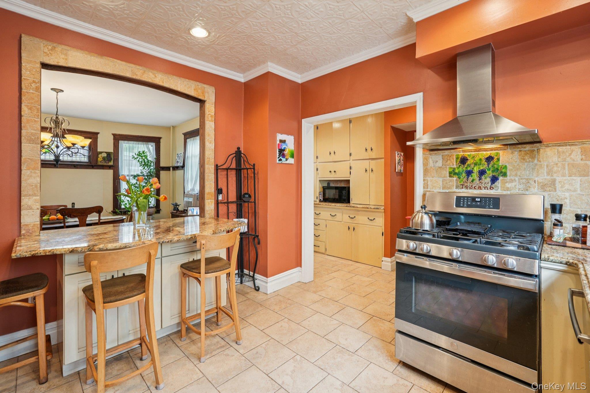 74 East Maple Avenue Suffern, NY 10901 - Photo 17 of 50 Kitchen featuring stainless steel gas stove, wall chimney range hood, crown molding, light stone countertops, and an ornate ceiling