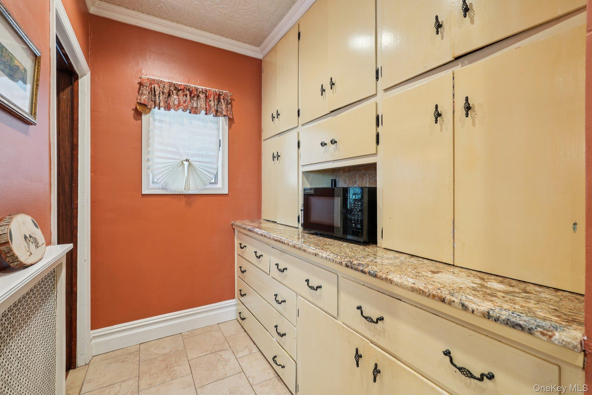 74 East Maple Avenue Suffern, NY 10901 - Photo 18 of 50 Kitchen featuring cream cabinetry, an ornate ceiling, ornamental molding, radiator heating unit, and black microwave