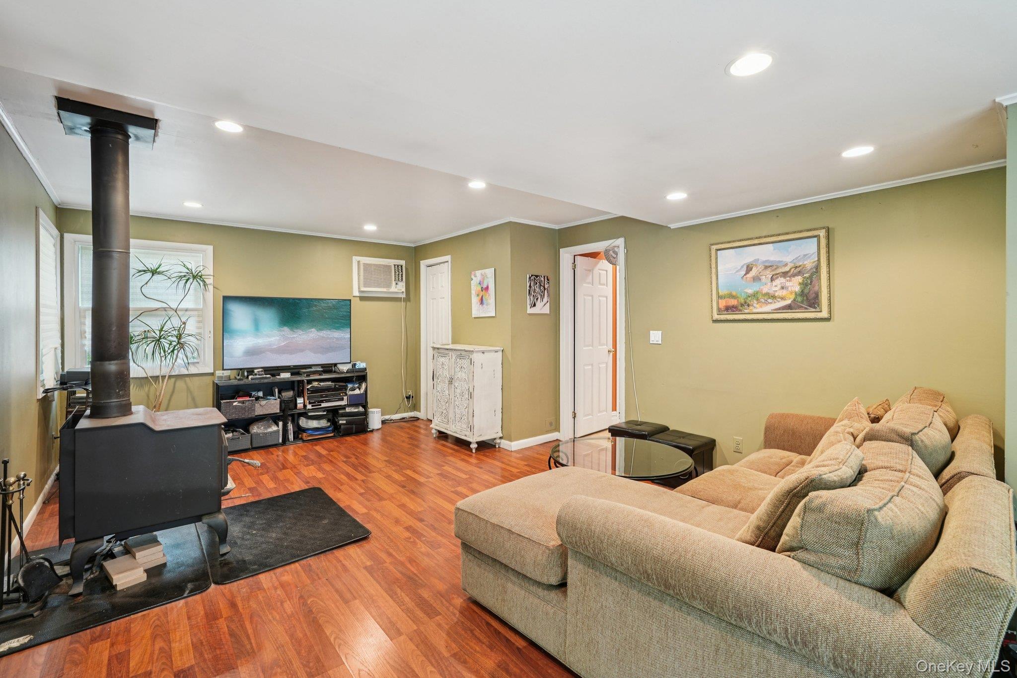 74 East Maple Avenue Suffern, NY 10901 - Photo 20 of 50 Living area with a wood stove, recessed lighting, ornamental molding, wood finished floors, and a wall mounted air conditioner