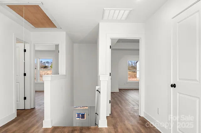 a view of a hallway with wooden floor and a bathroom