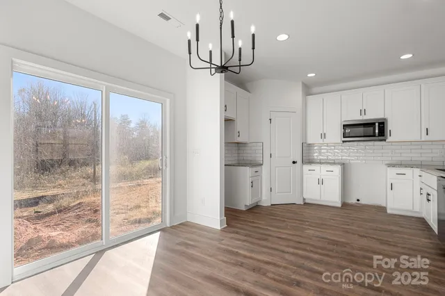 a kitchen with white cabinets and wooden floor