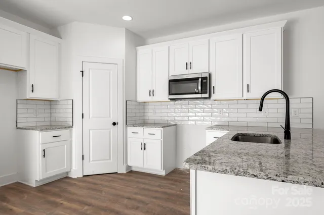 a kitchen with granite countertop a sink and a stove top oven with wooden floor