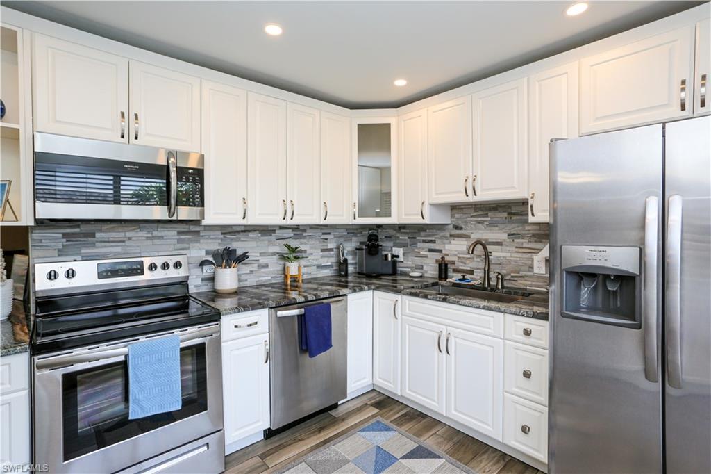 195 Peppermint Lane, Unit 884 Naples, FL 34112 - Photo 19 of 50 a kitchen with stainless steel appliances granite countertop a stove a sink dishwasher a refrigerator and white cabinets