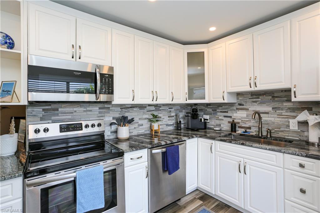 195 Peppermint Lane, Unit 884 Naples, FL 34112 - Photo 20 of 50 a kitchen with stainless steel appliances granite countertop a stove a sink and white cabinets