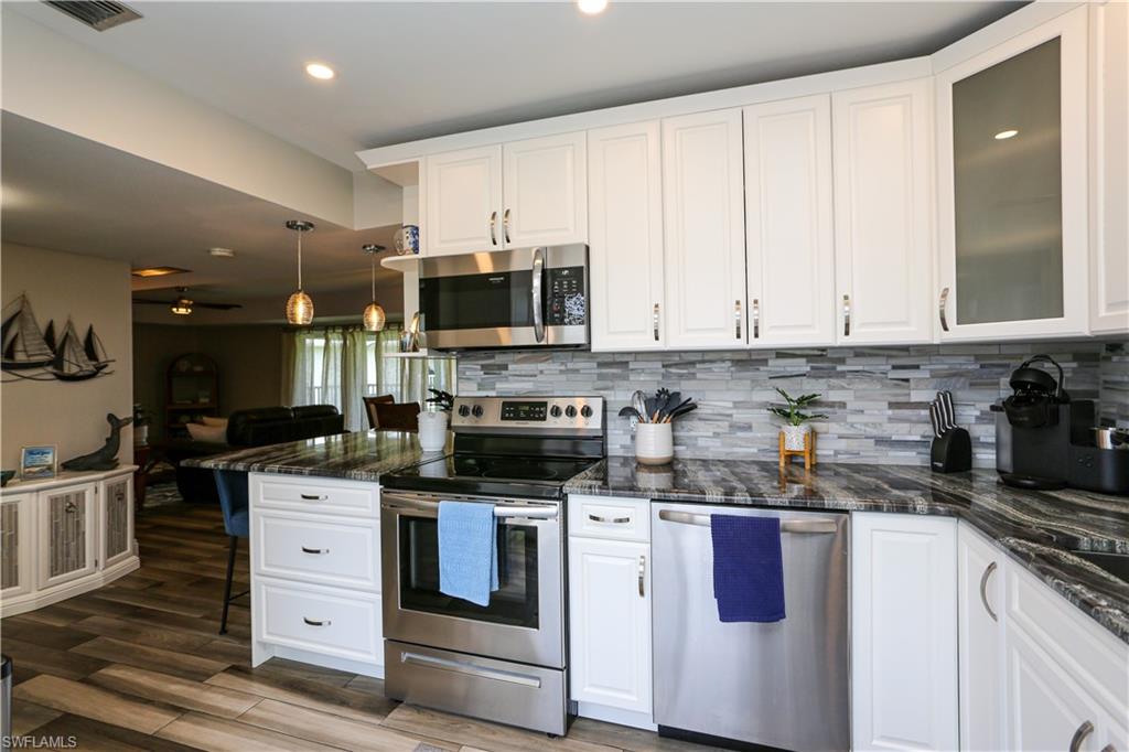 195 Peppermint Lane, Unit 884 Naples, FL 34112 - Photo 21 of 50 a kitchen with stainless steel appliances granite countertop a stove a sink and a microwave