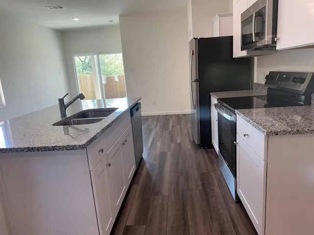 a kitchen with granite countertop a sink stove and refrigerator