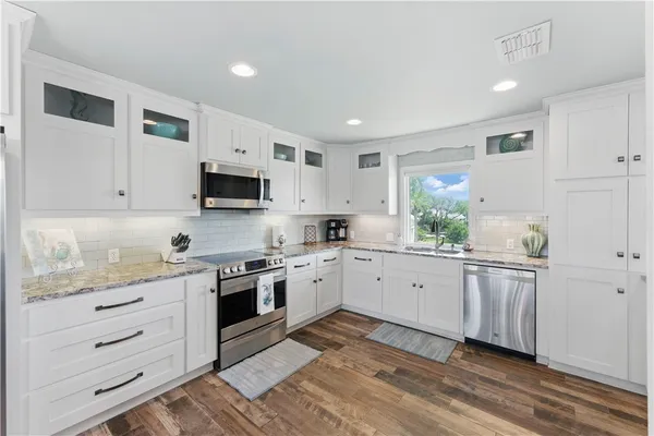 a kitchen with granite countertop white cabinets and white appliances