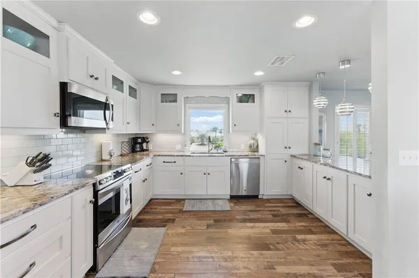 a large white kitchen with stainless steel appliances granite countertop a large stove top oven and cabinets