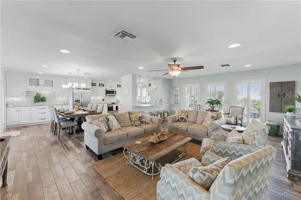 a living room with couches and kitchen view with wooden floor