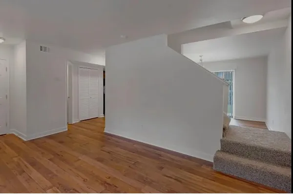 a view of an empty room with wooden floor and a potted plant