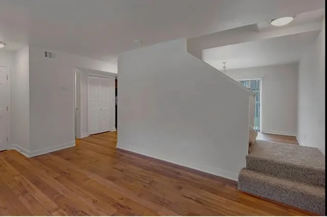 a view of an empty room with wooden floor and a potted plant