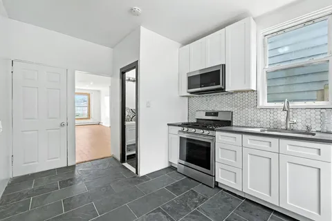 a kitchen with granite countertop a sink cabinets and stainless steel appliances